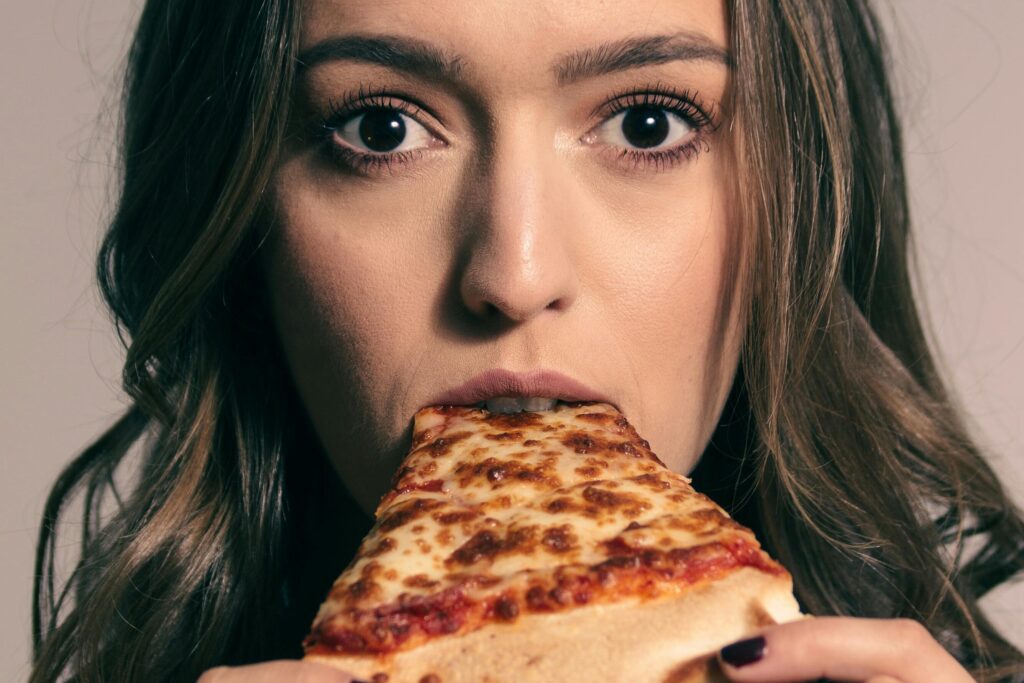 girl eating slice of pizza